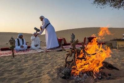 guests relaxing on sofa, and bbq served to them on sofa and table on a vip desert safari dubai